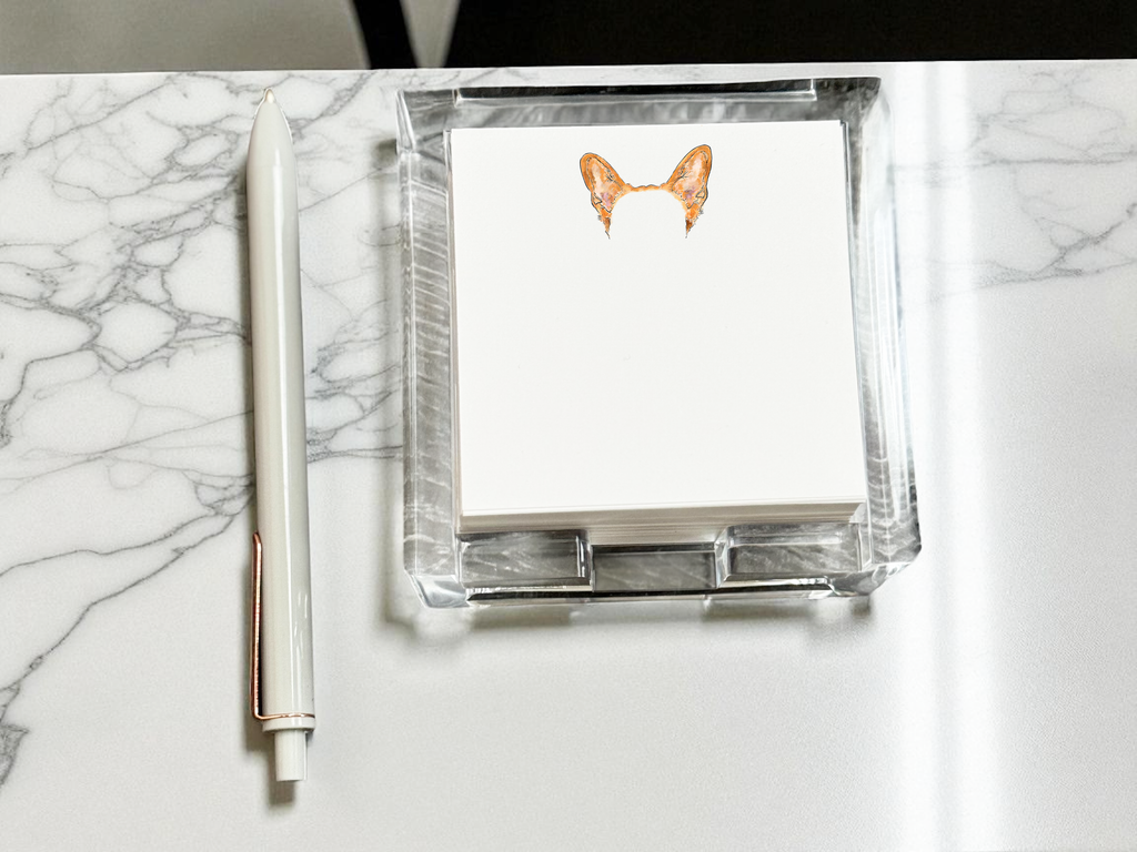 Acrylic notepad holder with note paper with color pet ears illustration on a marble surface
