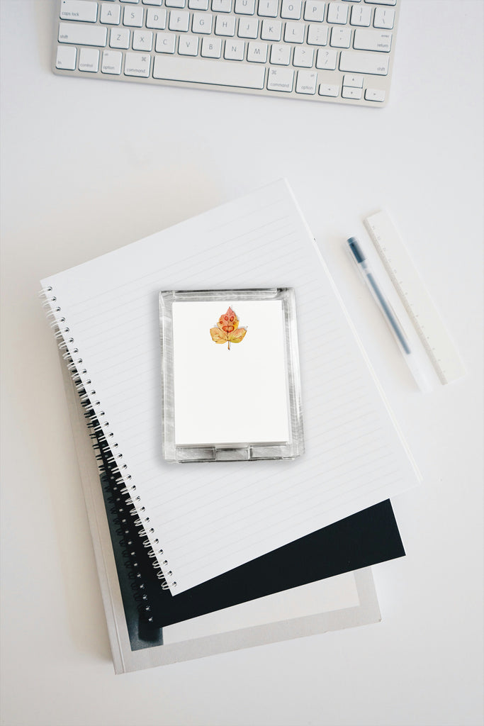 Custom acrylic notepad holder with paw print on leaf design, pen, and keyboard on a light surface