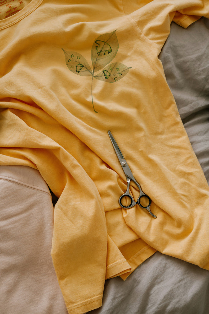 Yellow fabric with leaf/custom paw print  pattern and scissors on a bed
