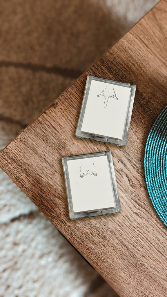 Two transparent acrylic notepad holders with sploot prints on a wooden surface.