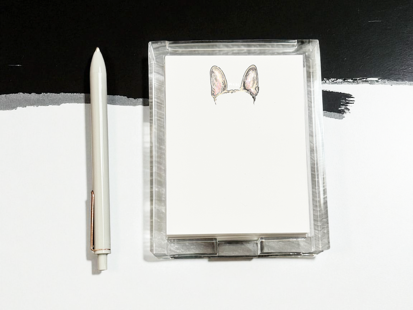Clear acrylic notepad with color dog ears and a pen on a black and white background