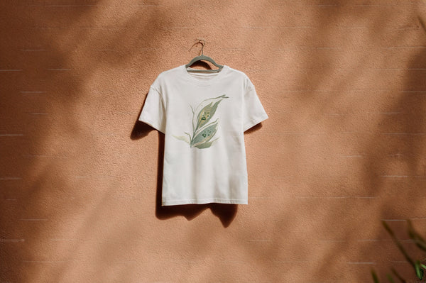 White t-shirt with a leaf paw design on a hanger against a brown wall