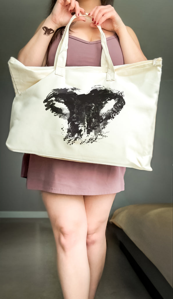 Person holding a tote bag with a black customized dog or cat nose print design against a neutral background