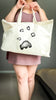 Person holding a tote bag with paw prints impression design on a plain background