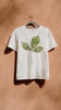 White t-shirt with green leaf with paw prints design on a hanger against a brown wall