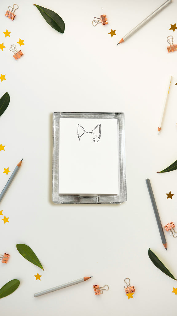 Acrylic notepad with a pet earsillustration surrounded by pencils, leaves, and decorative items on a white background