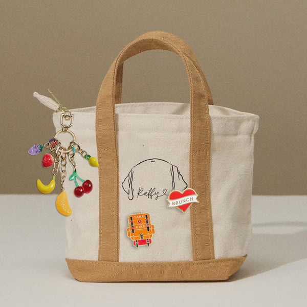 The Mini Eco Charm Tote is a sleek and compact bag designed for effortless everyday use. Crafted from eco-friendly, durable cotton canvas, this bag is lightweight yet sturdy, making it a perfect choice for those who need a stylish, minimal carry-all. 