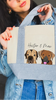Person holding a mini tote bag with dog portraits and text