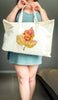 Person holding a tote bag with custom paw print leaf design against a neutral background