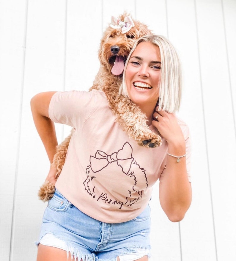 Custom Dog, Cat, or Other Pet's Ears Custom from Photo Outline Tattoo Inspired T-Shirt - Woman Wearing a Peach T-Shirt Holding a Goldendoodle Shown